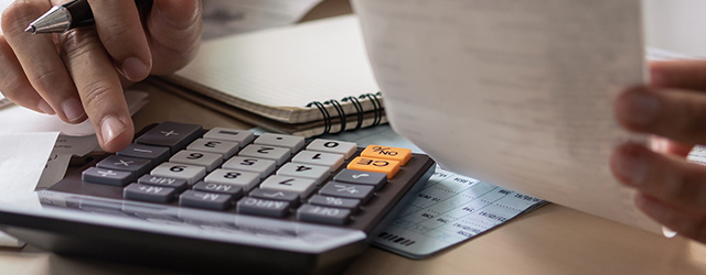 person at desk with calculator